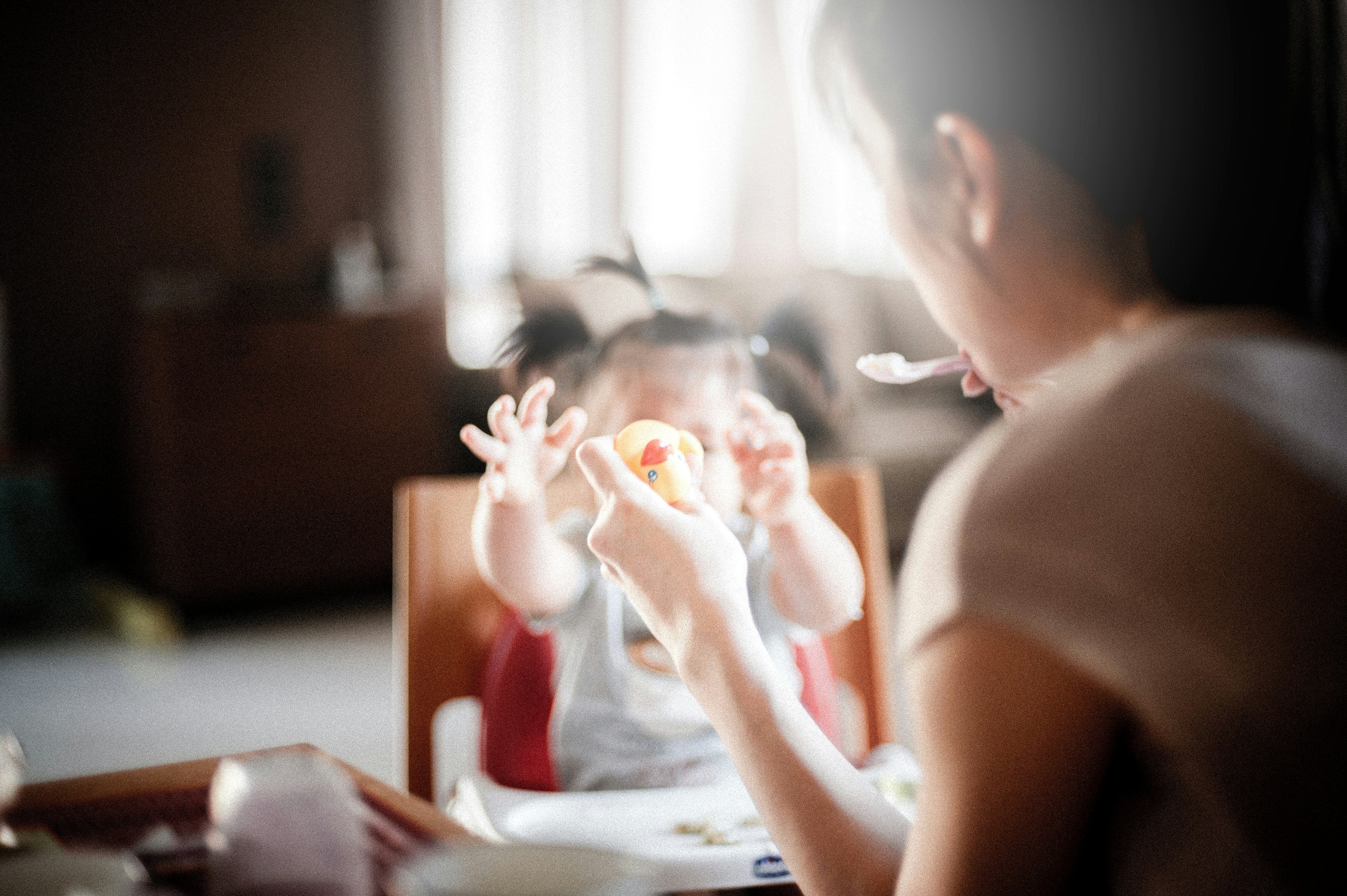 A parent feeding a child in a highchair